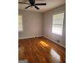 A bright bedroom with beautiful wood floors, a ceiling fan, and two windows that provide natural light at 7588 Covington Hwy, Lithonia, GA 30058