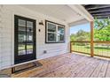A covered porch with a wood floor has a 