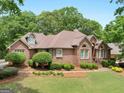 Well-maintained brick home with lush landscaping and mature trees around the manicured lawn at 1466 Lake Forest Ln, Mcdonough, GA 30253