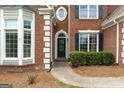 Close-up of a classic brick home showcasing a decorative bay window and arched front door with green shutters at 7020 Grand View Way, Suwanee, GA 30024