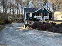 View of the front exterior, featuring a long driveway, front porch, and yard with mature trees at 177 Villa Rosa Way, Temple, GA 30179