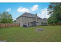 Large, grassy backyard featuring a patio with outdoor seating and a trampoline at 6697 Princeton Park Walk, Lithonia, GA 30058