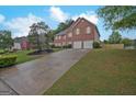 Spacious driveway leading to a brick home with a well-manicured lawn and garden beds at 6697 Princeton Park Walk, Lithonia, GA 30058