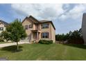 Lovely two-story home with well-manicured lawn, complemented by a young tree and lush green grass at 8045 Coleson Xing, Locust Grove, GA 30248