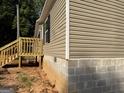 Side view of home showing siding, foundation, and wooden steps at 30 Alyssa Ln, Bowdon, GA 30108