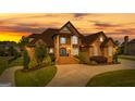 View of the exterior of the home at sunset showing the landscaped lawn and arched stone entryway at 770 Tralee Dr, Fayetteville, GA 30215