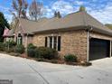 Brick home featuring a black two-car garage door, complementing black shutters, and a well-maintained landscape at 232 Darwish Dr, Mcdonough, GA 30252
