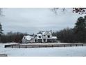 Beautiful two-story modern farmhouse with a stone chimney, black metal roof and snow covered yard at 155 Green Meadow Ln, Fayetteville, GA 30215