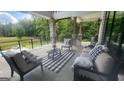 Covered patio with comfortable seating, outdoor views, stone columns, and black metal railing at 155 Green Meadow Ln, Fayetteville, GA 30215