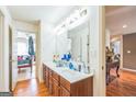 Bathroom featuring double sinks, a large mirror, wood cabinets, and hardwood floors at 3006 Gold Creek Dr, Villa Rica, GA 30180