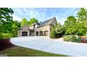 A three-car garage is attached to this brick house with a driveway winding to the street at 1345 Cashiers Way, Roswell, GA 30075