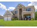 Elegant two-story home with brick and siding exterior, two-car garage, and a beautifully maintained lawn at 150 Gadson Dr, Fayetteville, GA 30214
