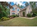 Stucco home with manicured lawn and landscaping and a front entry with an arched window at 215 Barrington Grange Dr, Sharpsburg, GA 30277