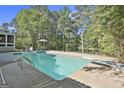 Backyard view of a sparkling swimming pool surrounded by mature trees and a concrete deck at 180 Willow Lake Ln, Sharpsburg, GA 30277