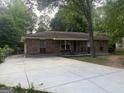 Charming brick home with a wide driveway, featuring a covered porch and gravel landscaping, and a mature tree in the front yard at 8145 Attleboro Dr, Jonesboro, GA 30238