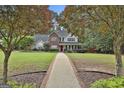 Inviting two-story home featuring a brick pathway, lush greenery, and mature trees at 908 Huntington Pl, Peachtree City, GA 30269