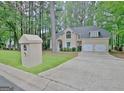 Beige two-story home with an attached two-car garage, nestled within a green wooded neighborhood at 302 Welton Way, Peachtree City, GA 30269
