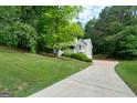 Residential home with a two-car garage and a long driveway surrounded by trees at 142 Pebblebrook Way, Temple, GA 30179