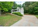 Home with a long driveway and two-car garage surrounded by trees at 142 Pebblebrook Way, Temple, GA 30179