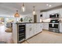 Modern kitchen with white cabinets, stainless steel appliances, granite countertops, island, and pendant lights, adjacent to the living area at 705 Berry Ct, Villa Rica, GA 30180
