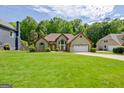 Exterior view of a home showcasing a well-maintained lawn, mature trees, and inviting curb appeal at 411 Baneberry Bnd, Peachtree City, GA 30269