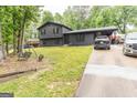 Charming two-story home with dark siding, metal roof carport, and swing set in the landscaped front yard at 870 The Cir, Lawrenceville, GA 30043