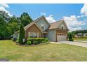 Lovely home showcasing stone and blue siding, complemented by a lush green lawn and an attached two-car garage at 207 Brookstone Dr, Carrollton, GA 30116