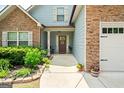 Inviting front porch adorned with stone accents, plants, and a charming door featuring the house number at 207 Brookstone Dr, Carrollton, GA 30116