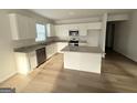 Bright kitchen with granite countertops, white cabinets, stainless steel appliances, and wood flooring at 2051 Blue Sky Ave, Covington, GA 30016
