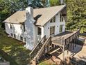 A view of the deck, chimney and backyard of the home with lush greenery, perfect for outdoor enjoyment at 1875 Bernice Dr, Cumming, GA 30041