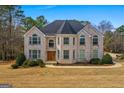 Beautiful two-story home with a brick facade, arched windows, mature trees, and a circular driveway at 1202 Persimmon Way, Mcdonough, GA 30252