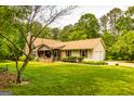 Charming home with stone chimney, lush yard, and attached garage offers comfortable suburban living at 130 Brooklet Way, Brooks, GA 30205