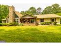 Inviting home with stone-accented porch and rocking chairs, surrounded by a well-manicured lawn and landscaping at 130 Brooklet Way, Brooks, GA 30205