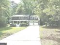 Two-story home with a long driveway and attached two-car garage, surrounded by lush greenery at 305 Glenloch Ln, Stockbridge, GA 30281