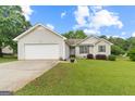 Charming one-story home with vinyl siding, attached garage, and a well-maintained lawn and landscaping at 1704 New Hope Rd, Locust Grove, GA 30248
