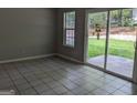 Living room with tile floors, a bright window and sliding door view to green backyard at 6260 Marbut Farms Ter, Lithonia, GA 30058