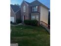 View of the two-story brick home showcasing the front lawn and side wooden staircase at 10937 Southwood Dr, Hampton, GA 30228