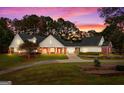Beautiful home with brick accents, landscaped yard, and a welcoming porch, bathed in the warm glow of evening lights at 228 Indian Creek Rd, Locust Grove, GA 30248