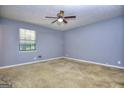 Neutral-toned bedroom features a ceiling fan, plush carpet, and natural light from the window at 2066 Tidwell Trl, Stone Mountain, GA 30088