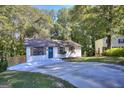 Landscaped front yard leads to a charming single-story home with a new concrete driveway and a wooded backdrop at 2066 Tidwell Trl, Stone Mountain, GA 30088
