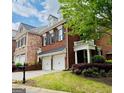 Red brick townhome with white columns, manicured lawn, and a two-car garage at 11945 Dancliff Trce, Alpharetta, GA 30009