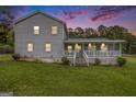 Elegant gray home with a welcoming porch, enhanced by a stunning sunset backdrop and well-kept lawn at 1125 Babbs Mill Rd, Hampton, GA 30228