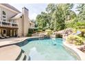 Resort-style pool and spa area featuring a rock waterfall, lush landscaping, and a tanning deck at 4090 Cooks Farm Nw Dr, Kennesaw, GA 30152