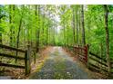 Tree-lined driveway leading through a lush forest with rustic wooden and metal gates at 3258 South Mckoy Rd, Villa Rica, GA 30180