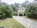 Two-story home boasts an attached carport, surrounded by lush greenery and mature trees at 815 Magna Carta Nw Dr, Atlanta, GA 30318