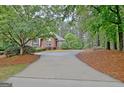 A long driveway winds through lush greenery, leading up to a charming brick home at 120 Hamilton Glen Ct, Fayetteville, GA 30215