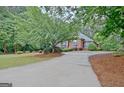 A glimpse of the brick home from the driveway showcases the landscape of the property at 120 Hamilton Glen Ct, Fayetteville, GA 30215