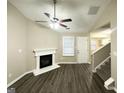 Cozy living room with hardwood floors, fireplace, ceiling fan, and ample natural light at 9151 Jefferson Village Sw Dr, Covington, GA 30014