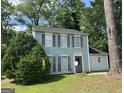 Charming two-story home with light blue siding and black shutters surrounded by mature trees at 4981 Millstone Walk, Stone Mountain, GA 30088