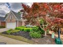 Brick home exterior showcases mature tree and well-maintained yard with a sprinkler system at 1880 Hickory Station Cir, Snellville, GA 30078